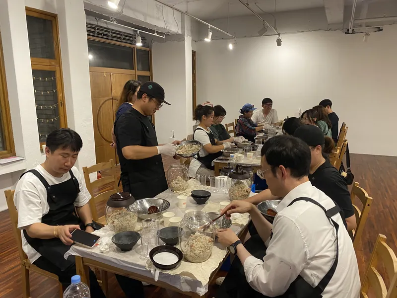 둘러앉아 고두밥과 누룩을 섞는 참가자들